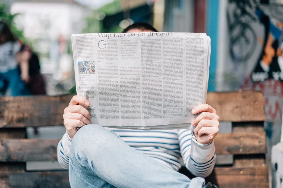 Reader relaxing with a newspaper on a bench