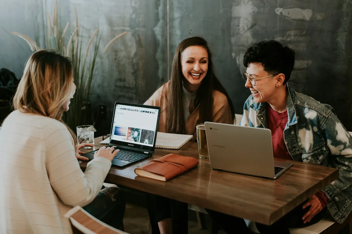 Three colleagues discussing ideas around a laptop