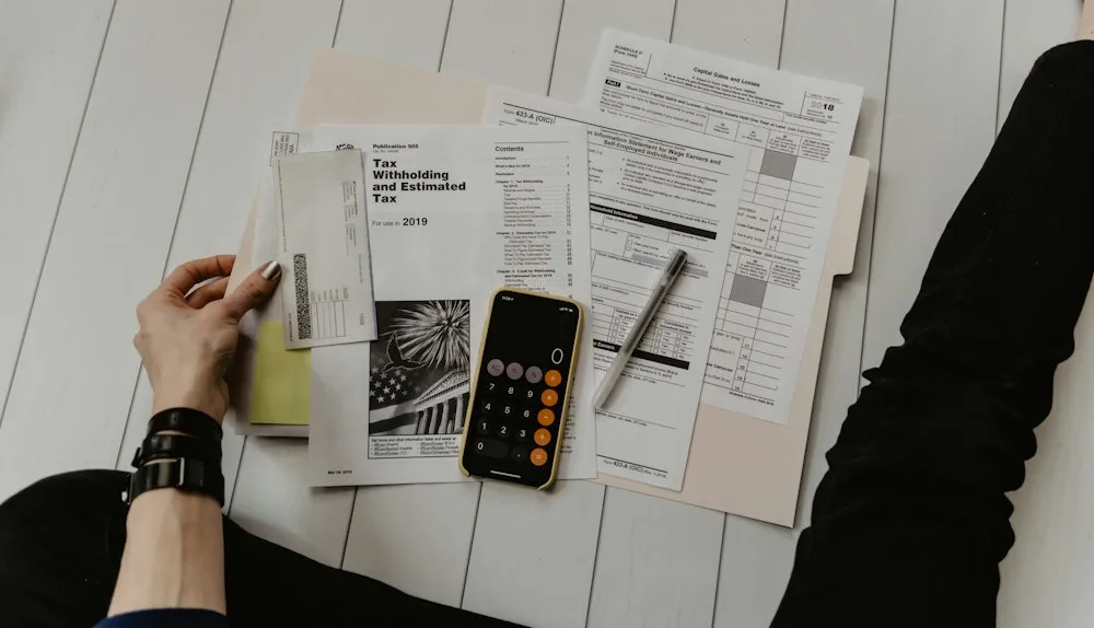 Person reviewing bills and tax forms with a calculator at a desk