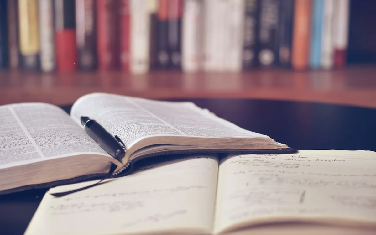 Open books on a library table with tall bookshelves in the background