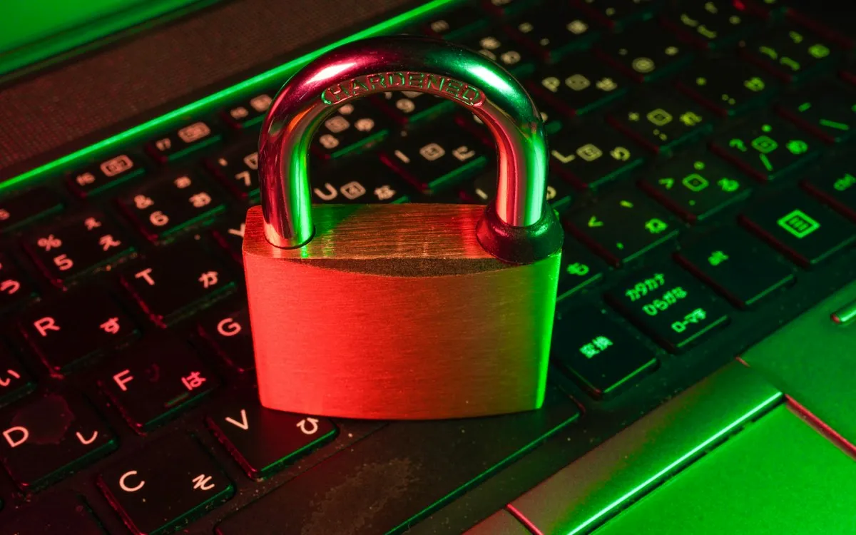 Red padlock resting on a laptop keyboard lit with green light